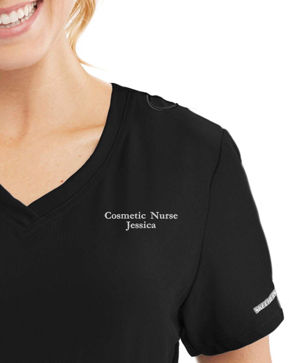 Text embroidery on scrub top — name and title stitched in white thread
